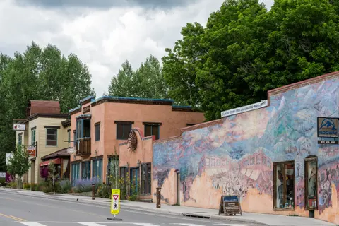 A street scene featuring storefronts and a large mural painted on a building wall.