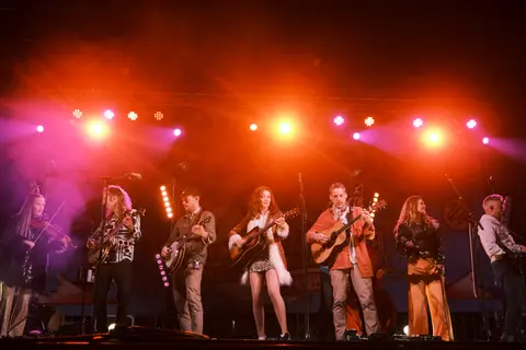 A band performs on a stage illuminated by bright lights.