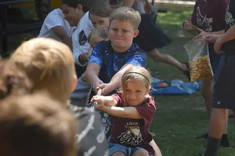 Children participating in a tug-of-war game outdoors.