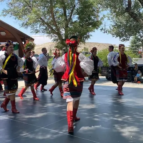 A group of dancers in traditional costumes perform outdoors.