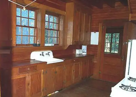 A photo of a rustic wooden kitchen interior with cabinets and a sink.