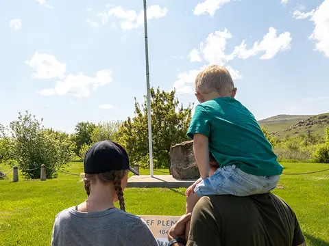 People look at a monument in an outdoor park setting.