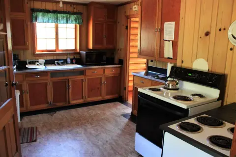 A rustic kitchen with wooden cabinets and appliances.