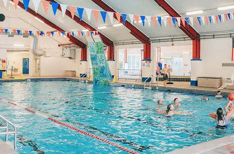 People enjoy swimming and playing in an indoor swimming pool.