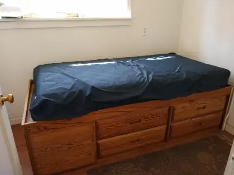 A wooden bed with drawers underneath is in a room.