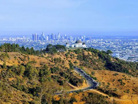 A view of a hillside observatory and a distant city skyline.