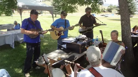 A group of people playing musical instruments outdoors on a sunny day.