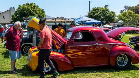 People gathered around classic cars at an outdoor car show.