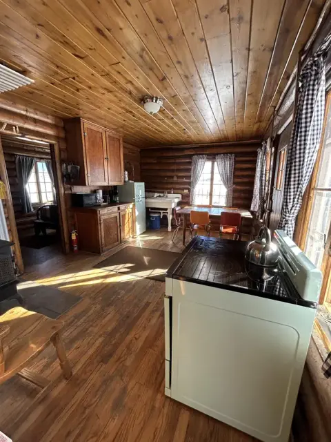 An interior view of a rustic log cabin kitchen with wood-paneled walls and ceiling.