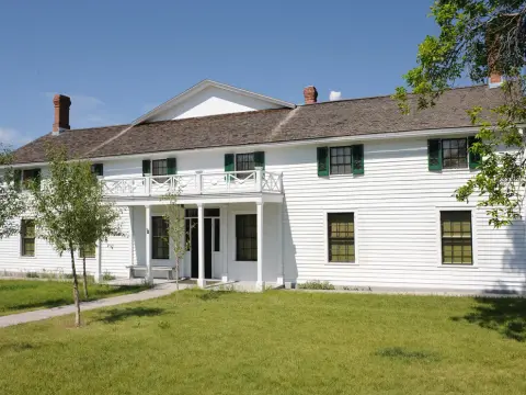 A large historic white building with green shutters and a second-story balcony.