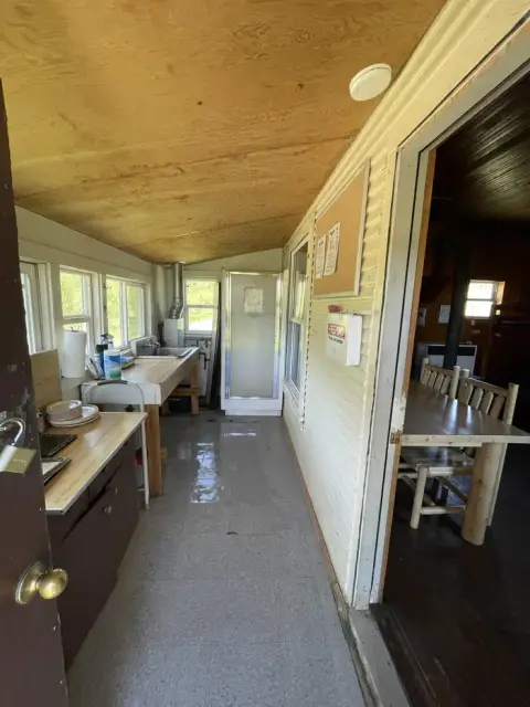 An interior view of a room with a counter, sink, and a doorway looking into another room.