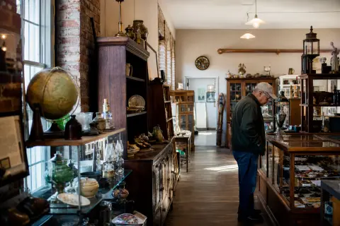 A man looks at items inside a display case in an antique shop.