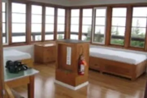 Interior view of a room with many windows and wooden furniture.