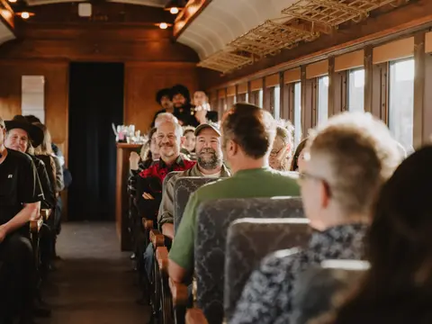 Passengers are seated inside a vintage train car.