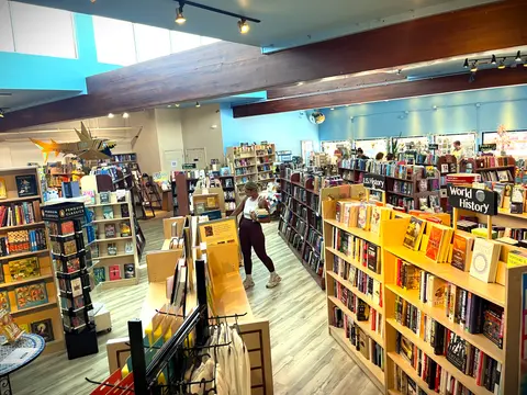 An interior view of a bookstore with packed bookshelves and a person browsing.