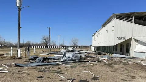 An outdoor view of a building with storm damage and debris scattered on the ground.