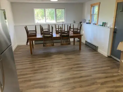 An interior room with a dining table and chairs flipped upside down on top of it.