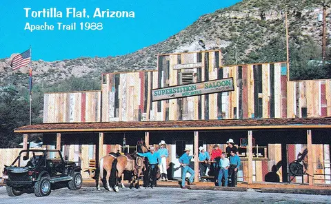 A historic photo showing a saloon exterior in Arizona with people and horses outside.