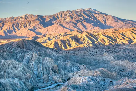A rugged desert landscape with mountains in the background.