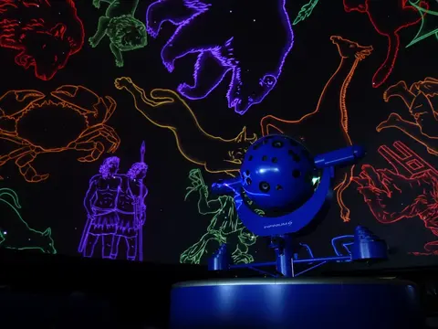 A planetarium projector with constellation projections in the background.