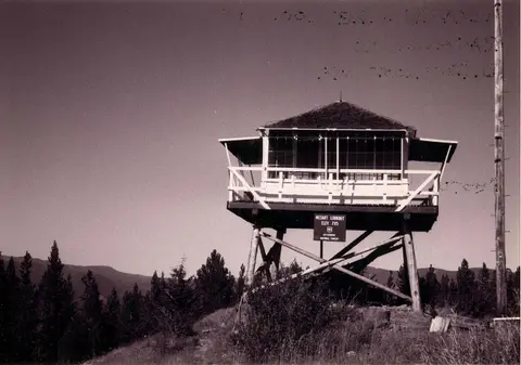 Black and white historic photograph of a fire lookout tower on stilts.