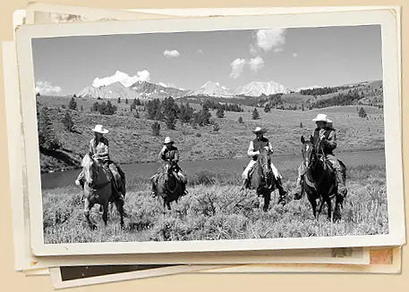 Black and white photo of four people riding horses in a mountainous landscape.