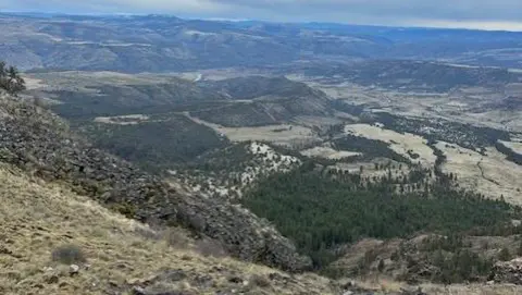 High-angle landscape view of hills, valleys, and distant mountains.