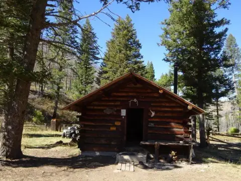 A rustic log cabin in a wooded area.