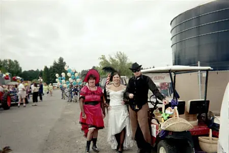 Three people in costumes stand outdoors next to a golf cart.