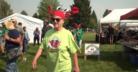 People walking around at an outdoor festival with vendor tents.