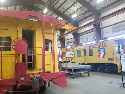 A photo showing the interior of a train museum or workshop with two yellow and red cabooses.