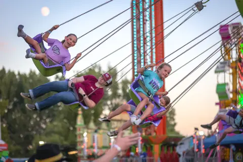 People enjoy riding a swing ride at a fair.