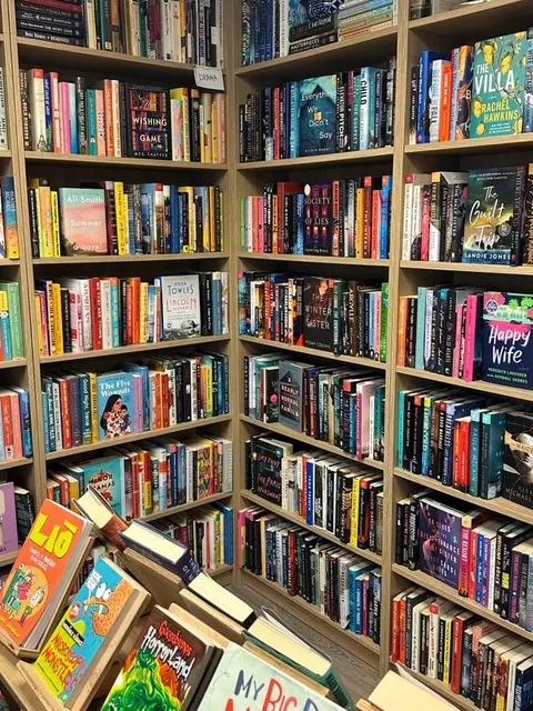 Wooden shelves filled with numerous books inside a bookstore or library.