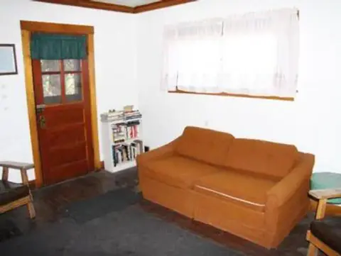 An interior view of a living room with an orange couch and a wooden door.
