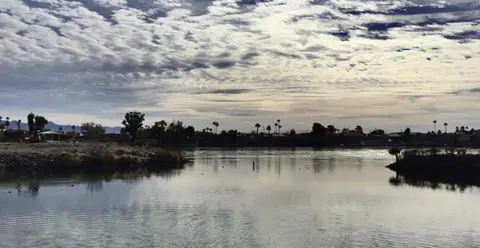 A calm body of water under a cloudy sky.