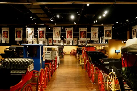 An interior view of a museum displaying various vintage carriages and buggies.