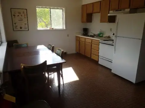 An interior shot of a kitchen and dining area with wooden cabinets and a dining table.