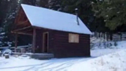 A small wooden cabin in the snow.