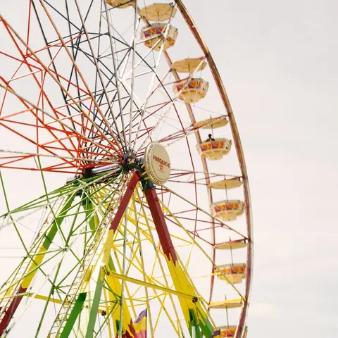 A colorful Ferris wheel stands against a bright sky.