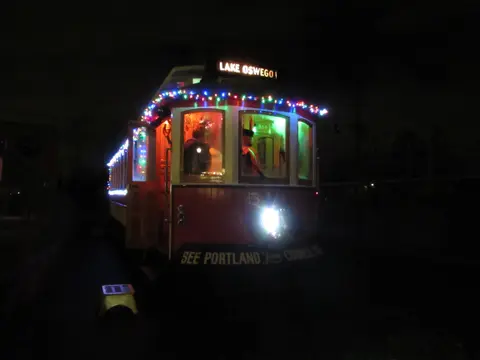 A streetcar decorated with colorful lights at night.