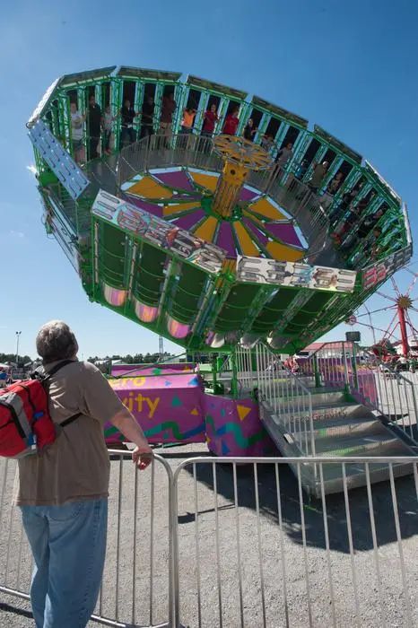 A person looks up at a spinning amusement park ride outdoors.