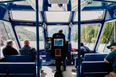 A view of the interior of a boat cabin with passengers looking out the windows.