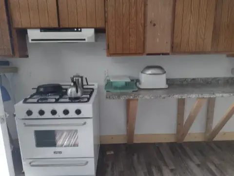 A kitchen with a stove, counter space, and wooden cabinets.