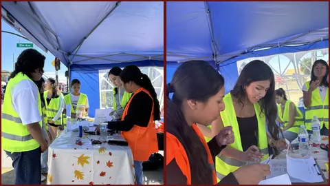 People working at a registration table under a blue canopy.