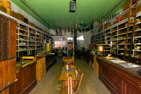 An interior view of a historic general store with wooden counters and shelves filled with goods.
