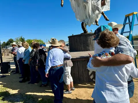 People gather outdoors near a large covered statue.