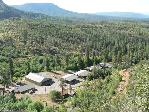 An elevated view of buildings nestled in a heavily forested valley with distant mountains.