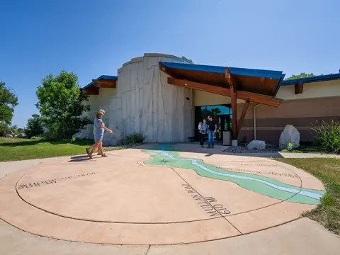 Exterior view of a modern building with a large painted map on the concrete walkway in front.