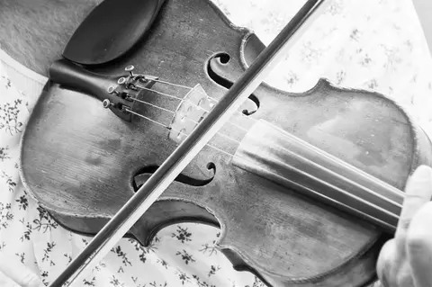 A close-up black and white photo of a violin being played.