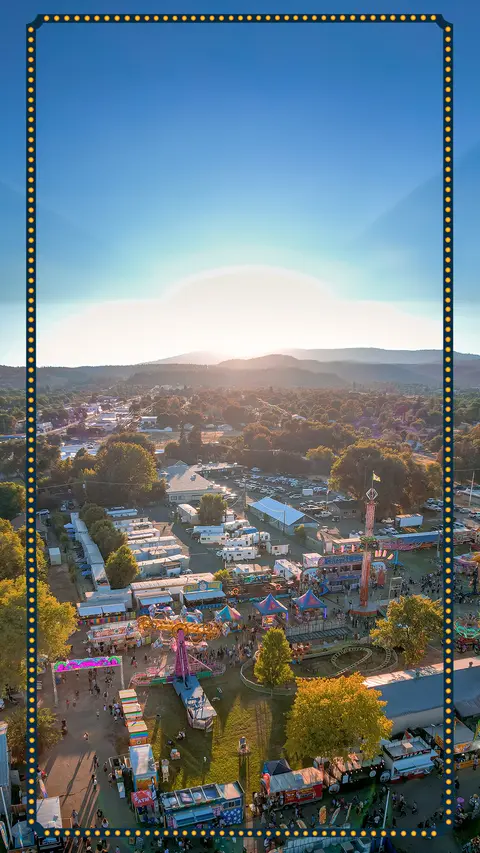 An aerial view of a fairground and surrounding town during sunset.